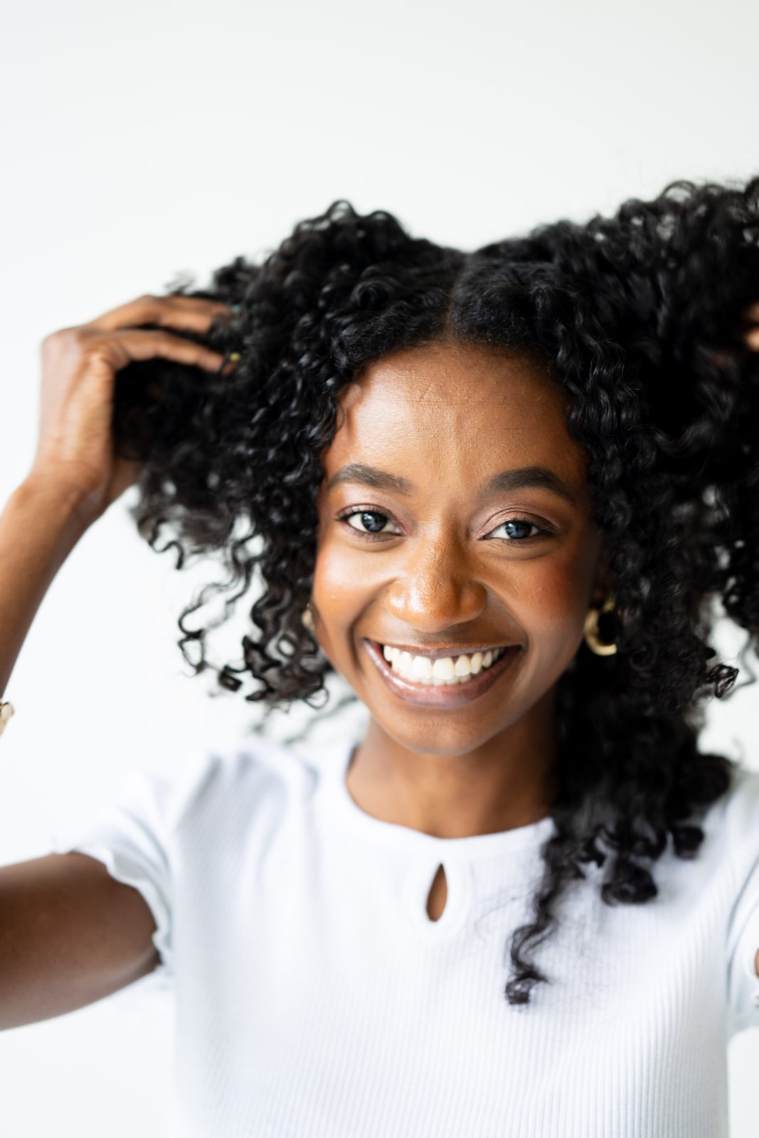 A woman smiling as she runs her fingers through her natural curls